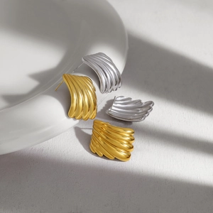 Gedetailleerd zicht op getextureerde waaiervormige oorknopjes in goud en zilver met schaduw