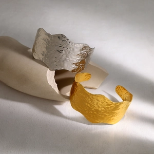 Moderne brede gehamerde roestvrijstalen armbanden met golvende randen in goud en zilver