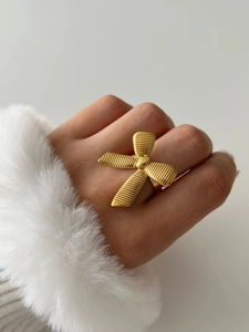 Detailed view of golden bow design ring with textured finish on a model's hand