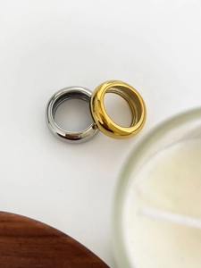 Nahaufnahme von minimalistischen gold- und silberpolierten Titanstahlringen auf Fläche