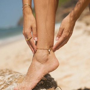 Tobillera de acero de titanio de 18K con perla de agua dulce en fondo de playa soleada