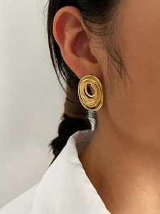 Primer plano de aretes en espiral dorados de varias capas con acabado pulido