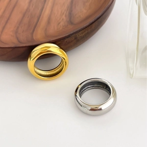 Polierte 18K Gold- und Silberringe auf einer minimalistischen weißen Oberfläche