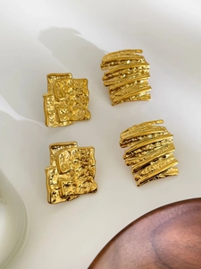 Detail van gouden geometrische oorknopjes met onregelmatige 18K metalen textuur afwerking