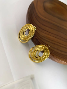 Primer plano de pendientes de espiral dorados con aros de acero de múltiples capas