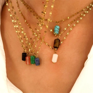 Macro view of colorful barrel stone pendants on fine gold chains for layering style