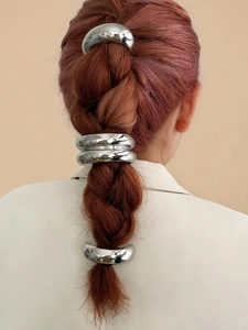 Dettaglio di anelli per capelli in argento su una treccia per uno styling raffinato