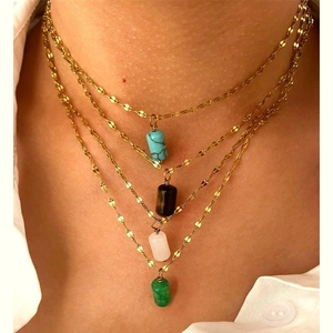 Close-up of four-layer gold stainless steel necklace with multi-colored natural stone pendants