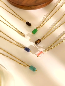 Detailed display of colorful natural stone cylinder pendants on thin gold chain necklaces