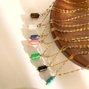 Detail of seven colorful natural stone cylinder pendants on gold stainless steel chains