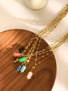Macro view of gold necklaces with colorful cylindrical natural stones on wood tray