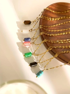 Detailed display of colorful natural stone pendants with golden chains on wood
