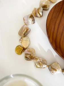 Macro shot of irregular baroque shell pearls and gold seashell pendant on white background