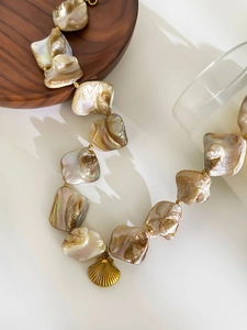 Macro view of baroque pearl necklace with golden shell pendant and golden spacers