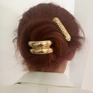 Elastici per capelli dorati a U e fermagli martellati su acconciatura a coda di cavallo