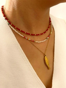 Detalle de un colgante de pez dorado en un collar de cuentas coloridas de varias capas