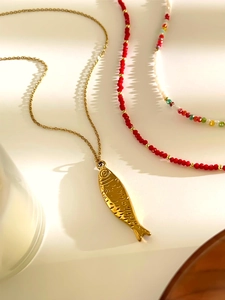 Detalle de colgante de pez dorado con cuentas de acrílico de colores y collares rojos