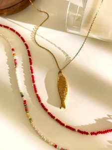 Detalle de colgante de pez dorado y cuentas de acrílico de colores en collares bohemios