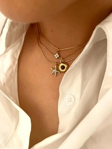 Detailed close-up of triple-layered gold necklace with starfish and flower zircon pendants