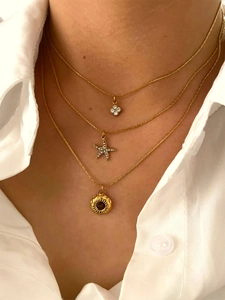 Detail view of gold layered necklace set featuring starfish, flower, and sun pendants