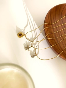 Detailed view of gold necklaces with starfish, sun relief, and flower charms