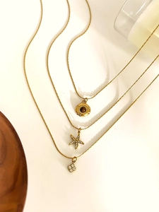 Detail of layered gold necklaces featuring starfish, sun motif, and flower charms