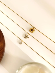 Detailed view of layered gold necklaces with starfish, flower and sunburst pendants