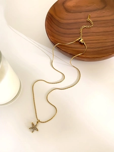 Close-up of a gold starfish pendant necklace with zircon inlay on a wooden display