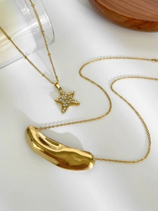 Macro detail of gold star pendant with rhinestones and smooth organic metal charm