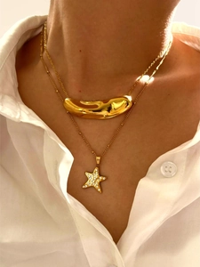 Detail of layered gold necklaces with polished irregular bean and rhinestone star pendants