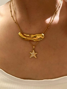 Close-up of layered gold necklaces with lava-effect pendant and rhinestone star detail