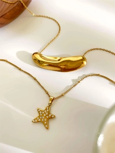 Detailed view of gold star rhinestone necklace and polished bean pendant in lifestyle setting