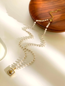 Dettaglio collana di perle con ciondolo a conchiglia dorato e intarsio in madreperla