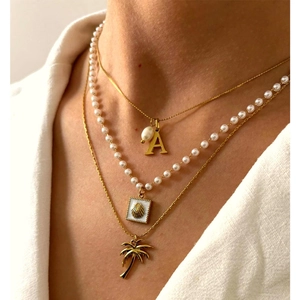 Collana a tre strati in oro con perla, ciondolo lettera A e charm a forma di palma