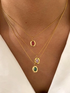 Three-layer gold necklace with oval green, red and pink gems worn by a model