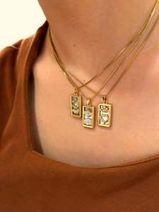 Detail view of rectangular tarot pendants with white shell inlay and gold plating