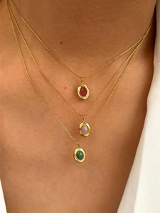Detail of triple-layered 18K gold necklace featuring emerald, purple, and red gemstones