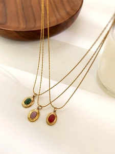 Detailed macro view of 18K gold-plated O-chains with emerald and ruby oval gemstones