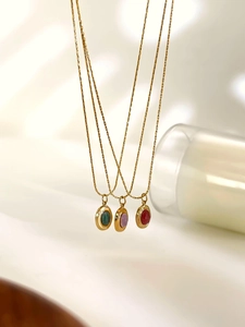 Detail showing gold plated necklaces with oval emerald, lavender and red gemstones