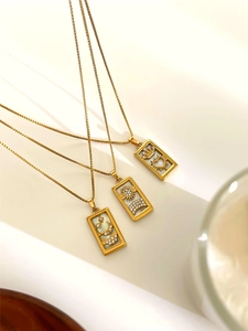 Detail view of three vintage gold necklaces with square tarot pendants and white stones