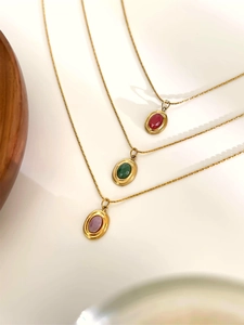 Detailed view of three 18K gold necklaces with oval red, green, and lavender natural stones