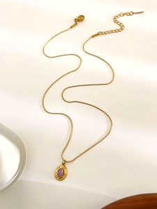 Detail of golden stainless steel necklace featuring a purple oval stone and lobster clasp