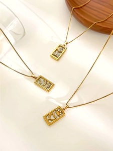 Detail of gold celestial tarot necklaces featuring sun, moon, and star charms with pearl shell