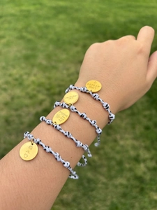Détail de bracelets réglables en cordon tressé avec des breloques dorées gravées de soleil