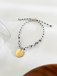 Détail du bracelet tressé ajustable avec pendentif doré gravé soleil et vagues