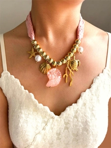 Dettaglio della collana in pizzo rosa con ciondoli a stella marina e conchiglia indossata