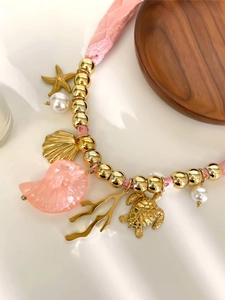 Dettaglio della collana estiva con stella marina dorata, tartaruga e cordino rosa