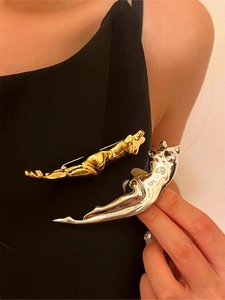 Artistic abstract human form brooch in polished gold and silver finishes on clothing