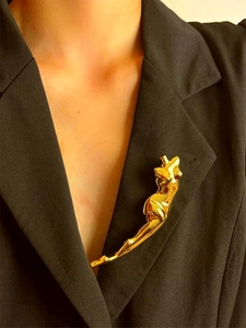 Artistic gold female body silhouette brooch pinned on a black suit blazer lapel
