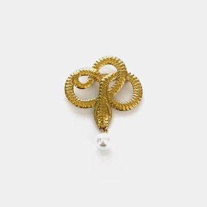 Detail of vintage gold snake brooch with textured scales and a white pearl drop accent